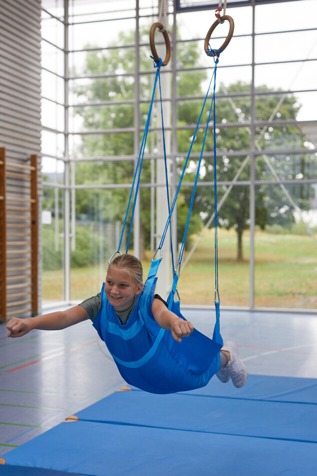 Flugschaukel mit Kind in einer Turnhalle
