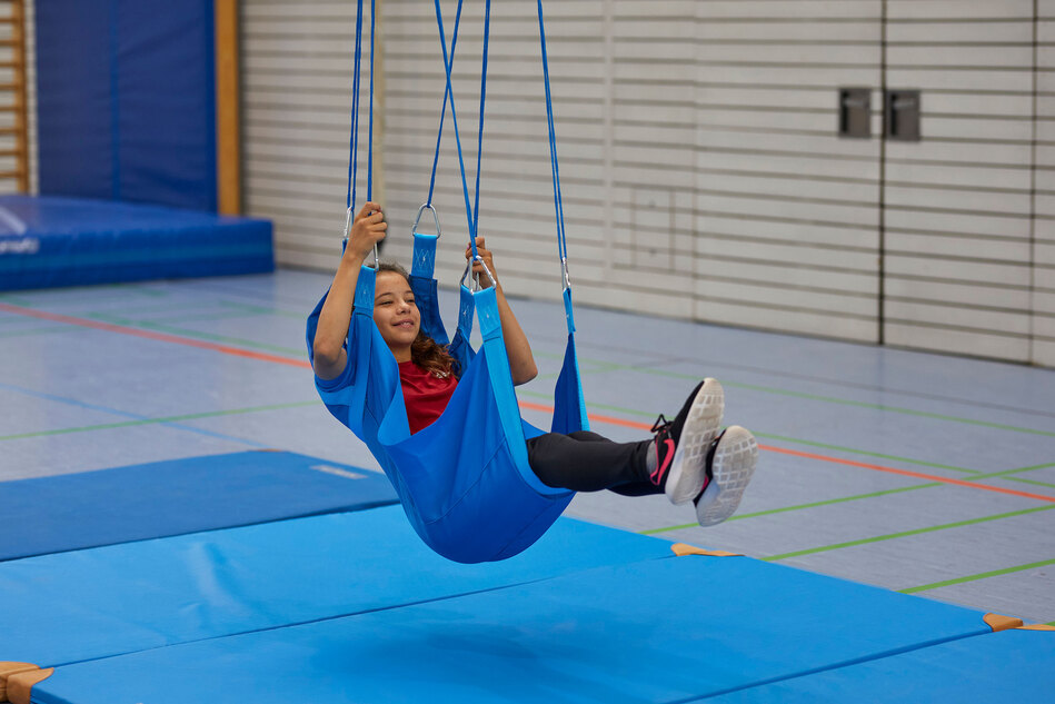 Flugschaukel mit Kind in einer Turnhalle
