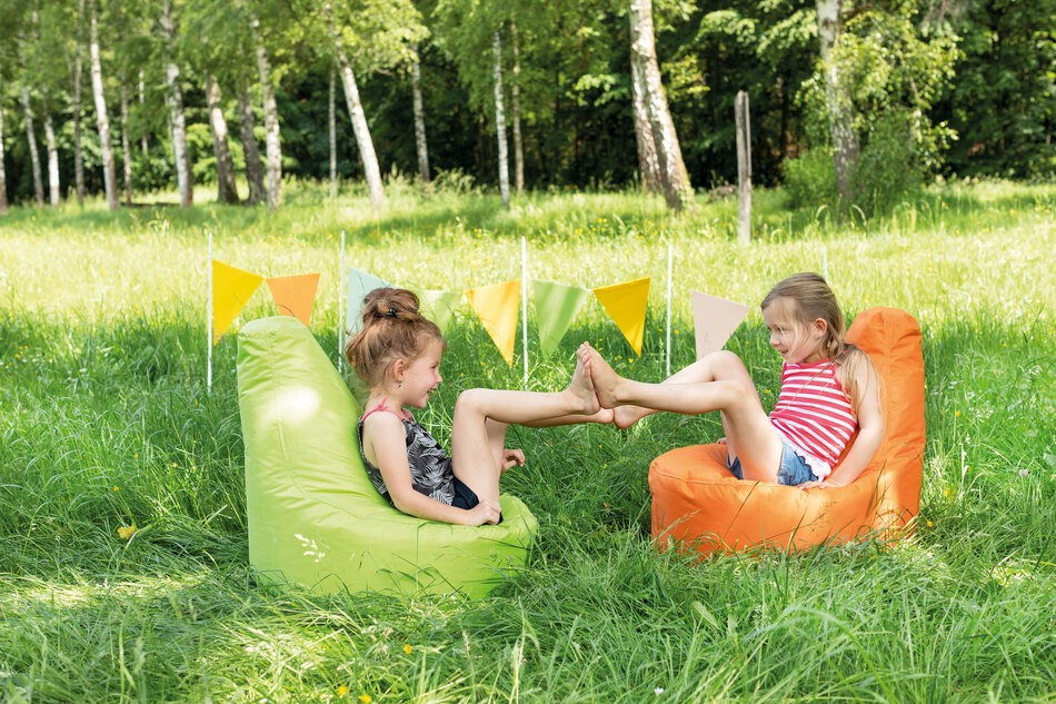 Kinder sitzen im Freien auf einem Sitzsack