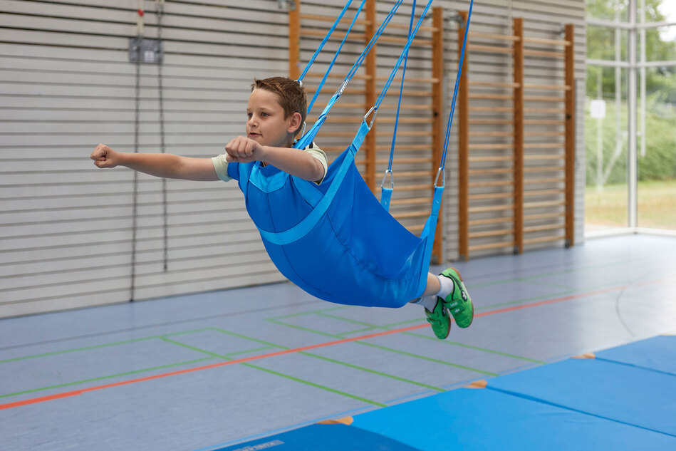 Flugschaukel mit Kind in einer Turnhalle