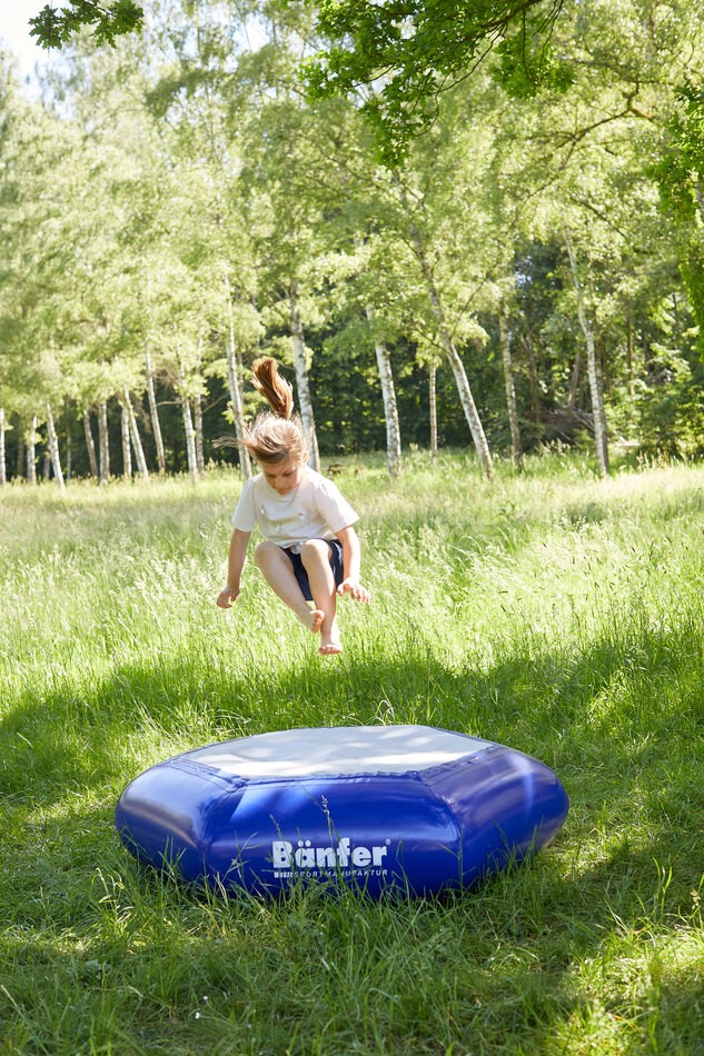 Hüppeding auf Wiese mit springenden Kind