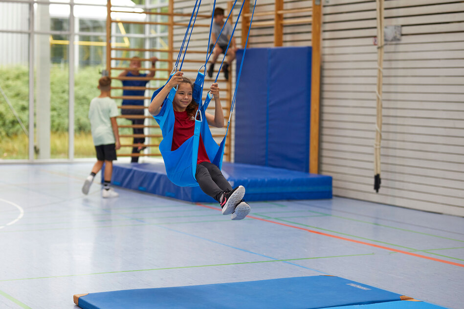 Flugschaukel mit Kind in einer Turnhalle