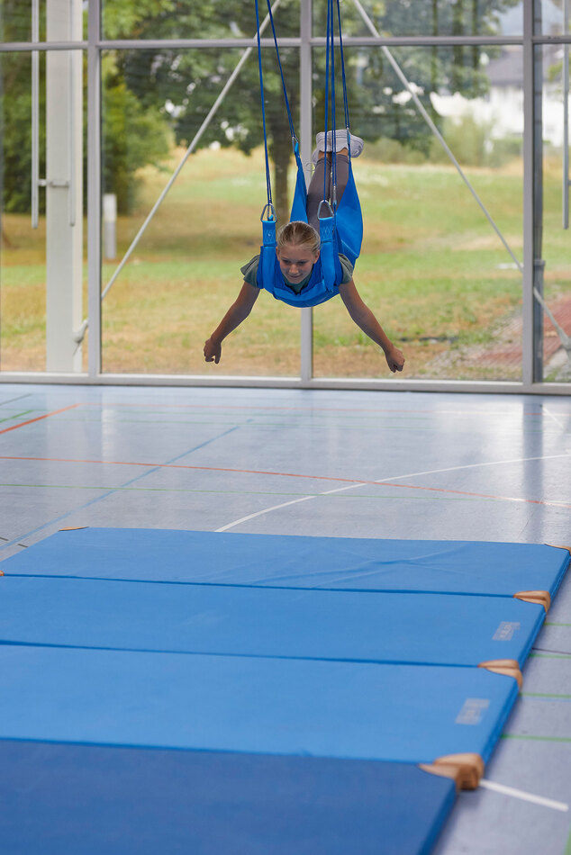 Flugschaukel mit Kind in einer Turnhalle