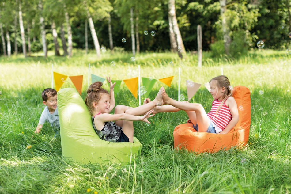 Kinder sitzen im Freien auf einem Sitzsack